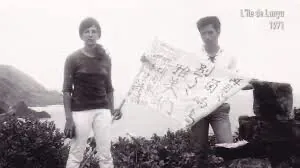 黑白老照片,两人站在海边礁石旁,一人展开一张写满字迹的大幅纸张,图片右上角水印文字「L'île de Lanyu 1971」