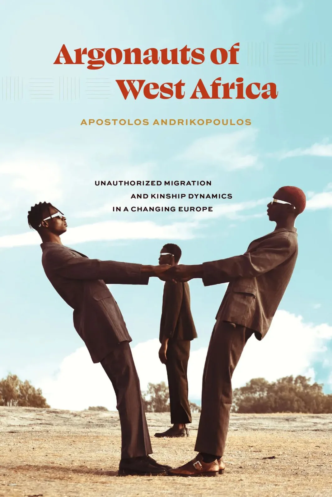 《西非的航海者》(Argonauts of West Africa)封面,两名身着西装的男子在沙地上向后倾身、以手相牵保持平衡,身后一人站立,背景是蓝天绿树。作者阿波斯托洛斯·安德里科普洛斯。