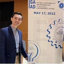 一名男子身穿西装,站在写有“全球无障碍宣传日 GAAD MAY 17, 2022”字样的展板旁留影。