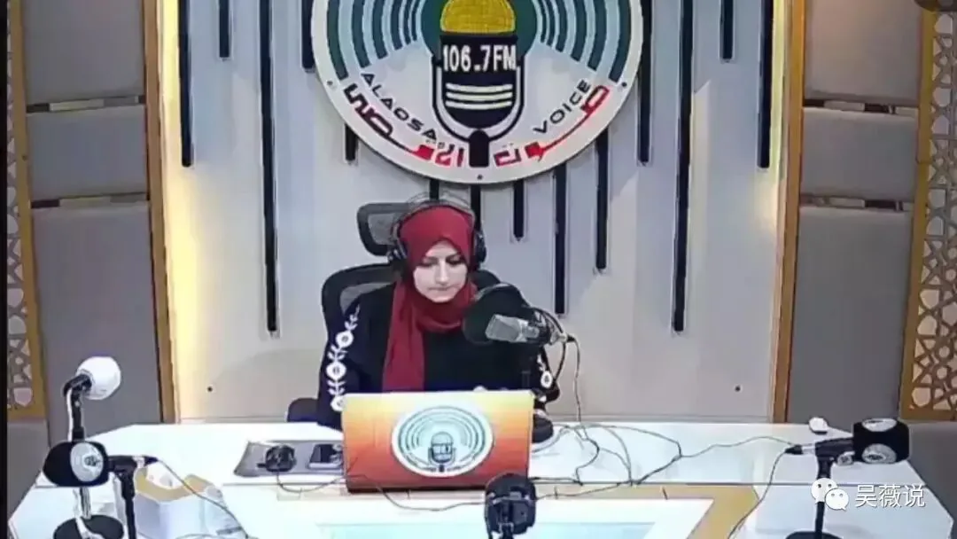杜阿·沙拉夫戴红色头巾与耳机,坐在阿克萨之声106.7FM广播台前工作。