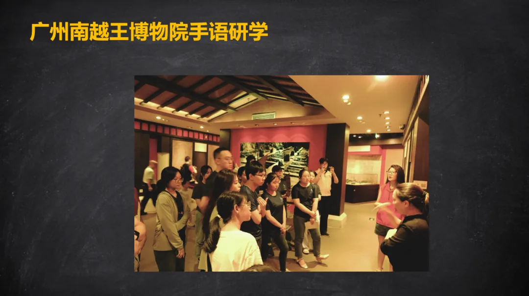 照片:一群参观者在南越王博物院展厅内围站,一名工作人员在右侧打手语讲解,学员们模仿或注视手势。