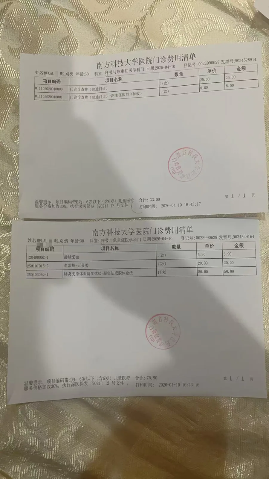 两张南方科技大学医院门诊费用清单摆放在织物上,分别记录挂号费、诊查费等门诊收费项目及金额,并盖有医院印章。