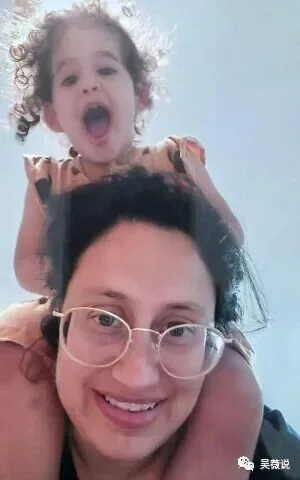 一名戴眼镜的女性与骑在她肩头的卷发幼童合影自拍,两人笑容灿烂。