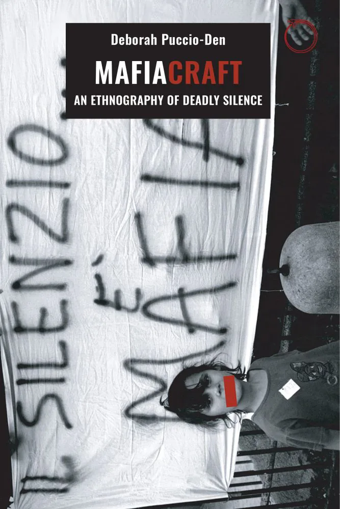 《黑手党之术》(Mafiacraft: An Ethnography of Deadly Silence)封面,作者黛博拉·普奇奥-登(Deborah Puccio-Den)。黑白照片旋转呈横向排布,一块白布上喷涂着意大利语标语「IL SILENZIO È MAFIA」(沉默即黑手党),下方一人的双眼被红色色块遮挡。