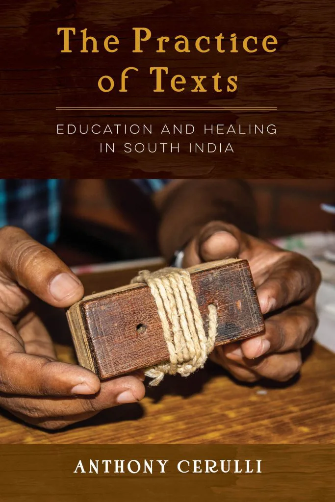 书封《The Practice of Texts: Education and Healing in South India》(文本的实践),作者安东尼·切鲁利,照片是双手捧着一本用麻绳捆扎的木质封面贝叶经典籍。