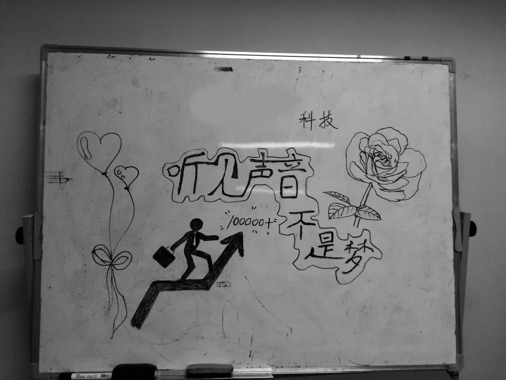 黑白照片,白板右上角另写有“科技”二字,上升箭头旁标注“100000+”。