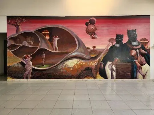 大型壁画描绘一只巨大蜗牛壳内嵌套着裸体人物与建筑场景,画面右侧站立着两个黑豹头人身形象,上方悬浮着形似蘑菇云的球状物,背景是粉红色天空。