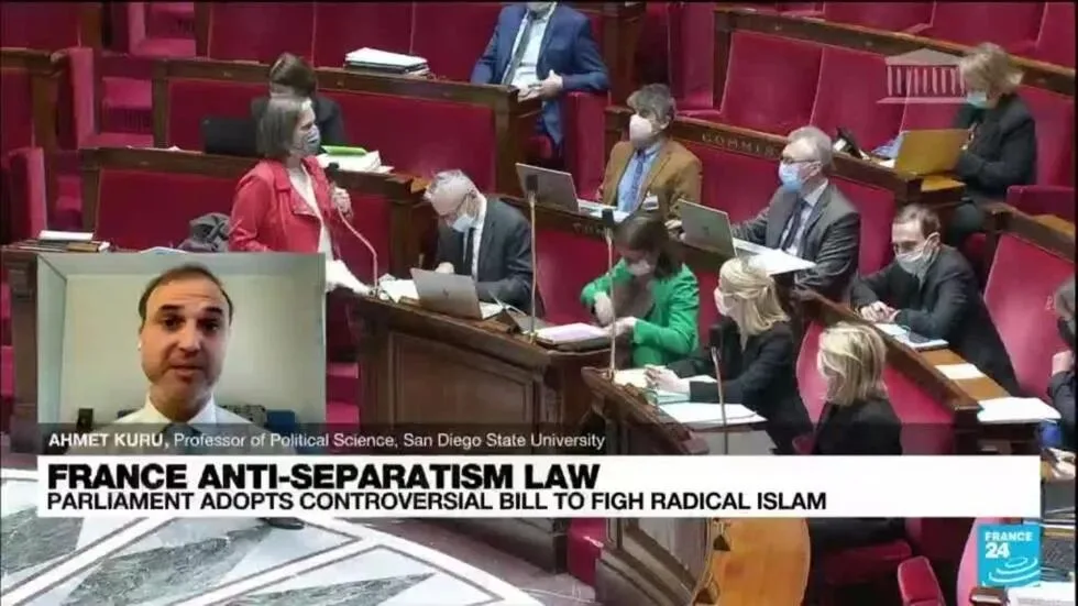 France24新闻画面:法国国民议会正在开会,议员们戴着口罩,左下角插播一位政治学教授的视频评论,底部字幕写着“法国反分离主义法:议会通过打击极端伊斯兰主义的争议法案”。