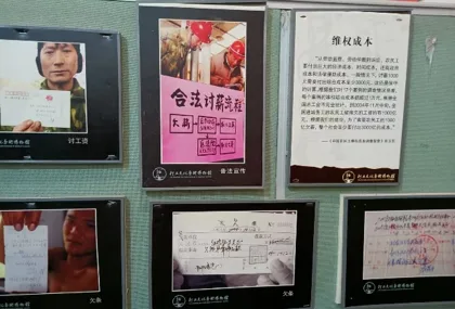 展墙陈列多幅图文,一张海报大字写着“合法讨薪流程”,一张说明牌题为“维权成本”,另有工人举牌讨薪的黑白照片,具体说明文字模糊难辨。