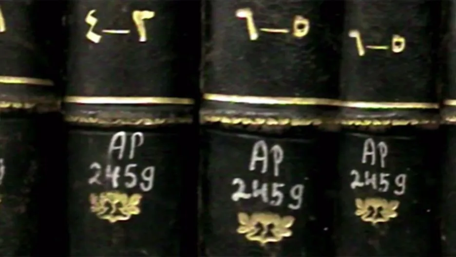 特写:几本深色皮质精装书脊烫金压花,贴着手写标签「AP 245g」,书脊上方另有希伯来字母编号。