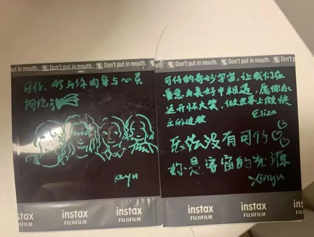 两张黑色即影即有照片,用荧光绿笔书写;左边画着四张卡通脸孔并签名“keyu”,右边写满祝福留言,落款可见“Eliza”与“xinyu”字样。